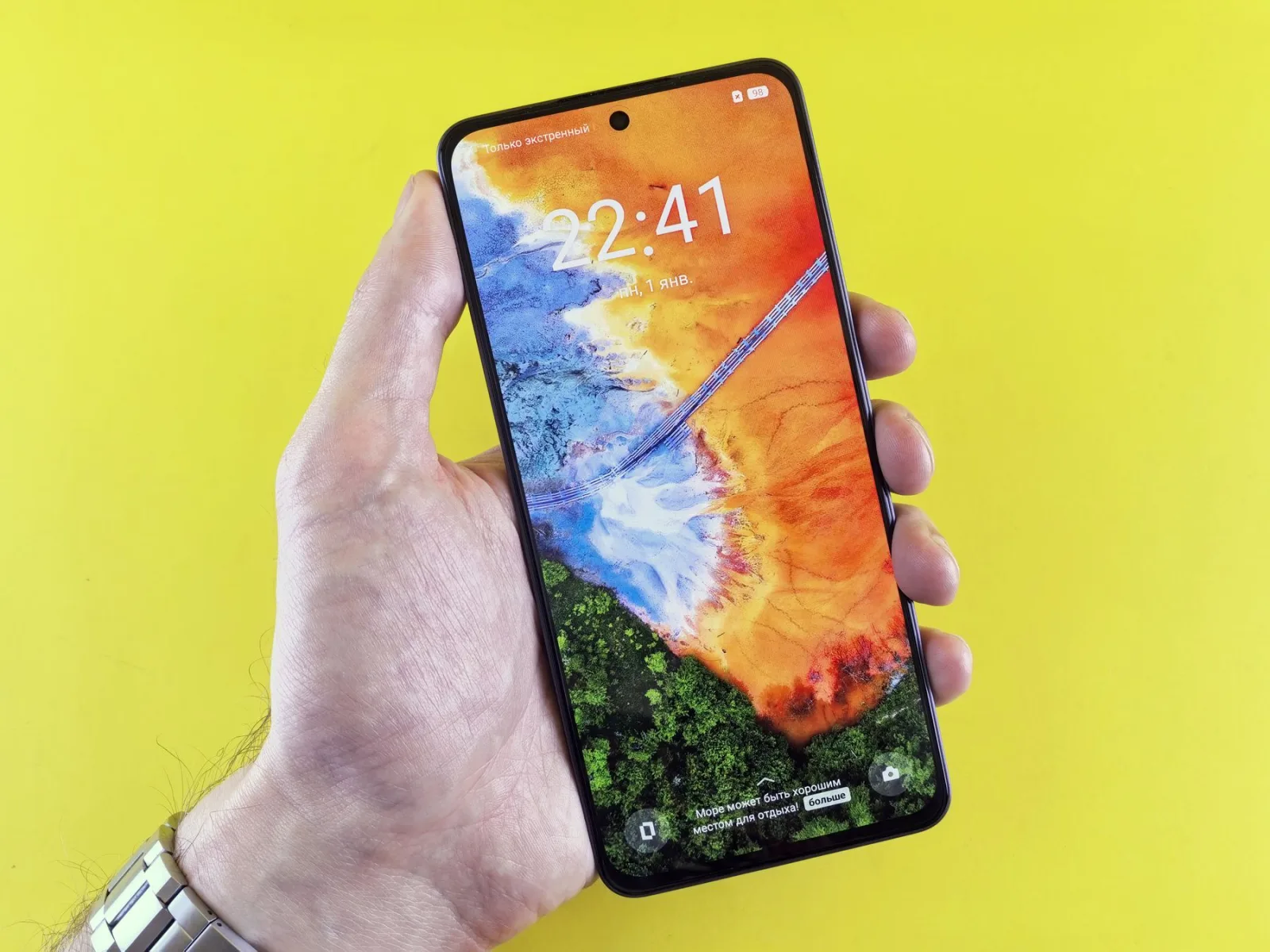 Celular na mão sobre fundo amarelo