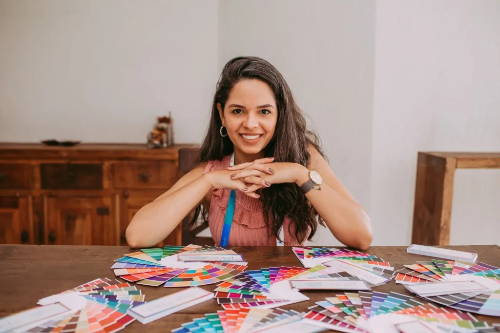 Designer sorrindo à mesa com leques de cores espalhados